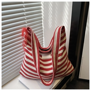 Detail of red and white striped knit tote bag with a decorative lace bow on white books