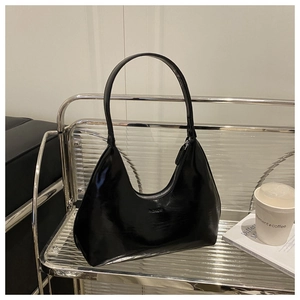 Close-up of black glossy hobo bag with embossed fashion text on a metal display