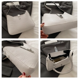 Detail view of white crocodile pattern tote with silver buckle and chain strap