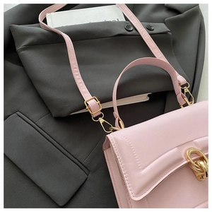 Detail of light pink crossbody bag with textured leather and gold chain metal clasp