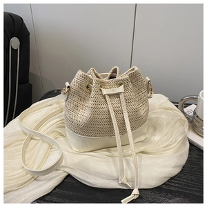 Detail of woven straw bucket bag with cream leather trim and drawstring closure