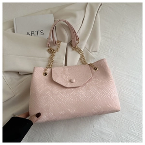 Détail du sac à main en cuir rose gaufré avec bandoulière chaîne sur tissu texturé