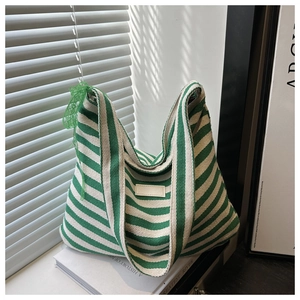 Detail of green and white striped knit tote bag with lace flower and textured fabric