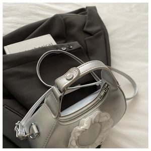 Close-up of silver crossbody bag featuring white lace detail and metallic finish