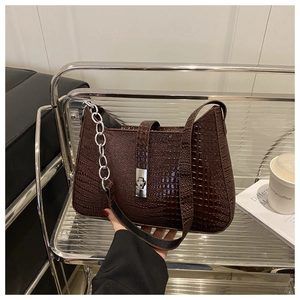 Close-up of deep brown crocodile pattern bag with silver chain and twist lock detail