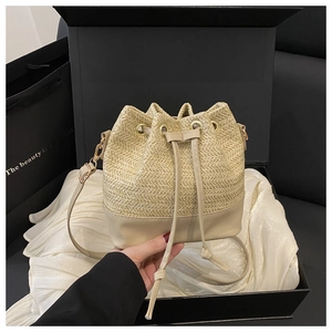 Detail of straw bucket bag inside gift box featuring drawstring closure and leather patchwork