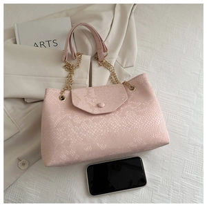 Détail du sac en cuir rose à motif serpent avec chaîne dorée et smartphone pour la taille