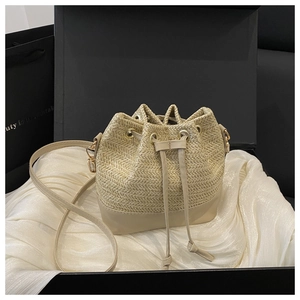 Detail view of woven straw bucket bag with leather base and drawstring closure in gift box