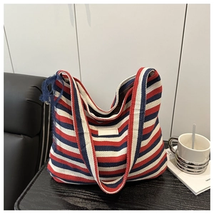 Gros plan d'un sac cabas en toile rayé rouge blanc bleu sur une table en bois sombre
