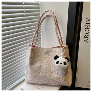 Pink jacquard tote bag detail with woven handles and cute panda plush keychain accessory