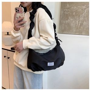 Détail du sac nuage en nylon noir avec bandoulière à volants et étiquette de mode