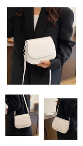 Detail of white saddle bag with FASHION TREND EST 1998 print and flip cover