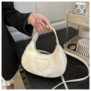 Detail showing lace heart decoration and pearlescent satin texture of the handbag