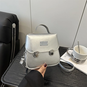 Sac à bandoulière argenté avec poignée supérieure en vue de dessus sur un bureau