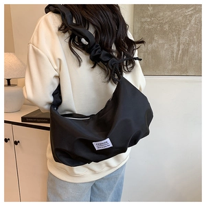 Détail du sac croissant en nylon noir avec une bandoulière plissée au style nuage élégant