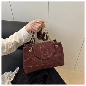 Détail d'un sac à main bordeaux à motif serpent avec une bandoulière en chaîne dorée