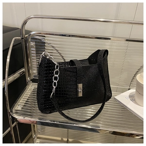 Detail of black crocodile texture shoulder bag with silver chain and metal buckle closure