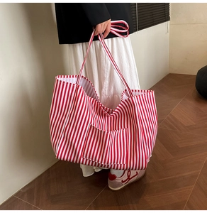 Detailed view of spacious red and white striped canvas tote bag held by a model