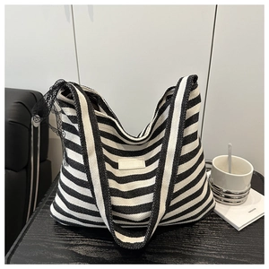 Détail du sac cabas à rayures contrastées avec nœud en dentelle noire et étiquette épurée
