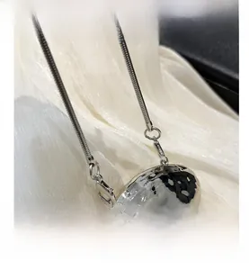 Close-up of a silver hammered metal pebble pendant with a sleek snake chain detail