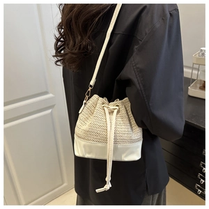 Model view of a straw bucket bag with white leather trim and golden metal hooks