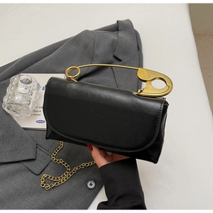 Detail of black square shoulder bag with oversized gold safety pin handle and chain strap