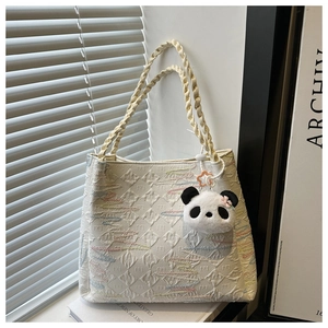 Detail of white embossed bucket bag with braided strap and cute panda charm accessory