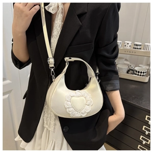 Detailed view of white dumpling bag with lace heart decoration and adjustable strap