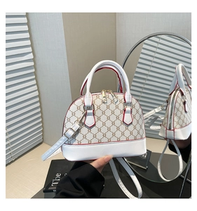 Detail of shell-shaped white leather bag with vintage brown pattern and gold zippers