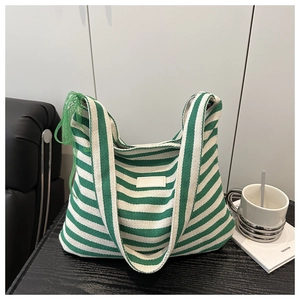 Détail du sac cabas en toile rayé vert et blanc avec un nœud décoratif en dentelle sur l'anse