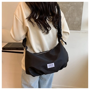 Gros plan du sac bandoulière noir avec étiquette fashion et cordon de serrage minimaliste