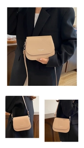 Close-up of beige saddle bag with 'FASHION TREND EST 1996' text and adjustable strap
