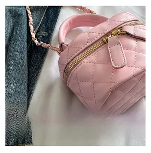 Detail der rosa gesteppten Mini-Box-Tasche mit Metallkettenriemen und Tragegriff