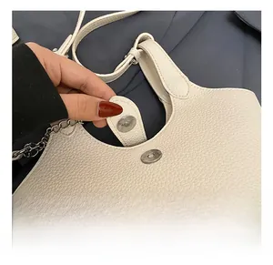 Detail of cream bucket bag showing silver magnetic closure and lychee grain leather