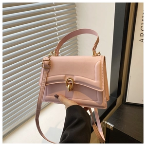 Detailed view of pink leather handbag with gold circular lock and geometric embossed lines