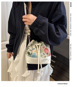 Close-up of a floral embroidery bucket bag with white leather drawstring and long strap