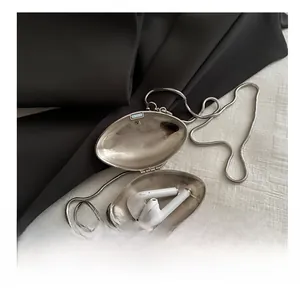 Macro view of silver shell-shaped mini chain bag showing storage capacity for earbuds
