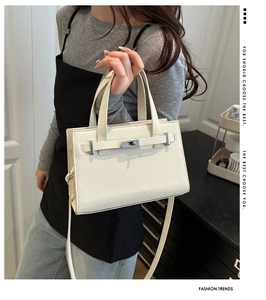 Close-up of white lychee textured handbag featuring silver hardware and a turn-lock closure
