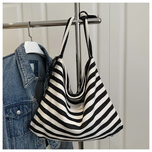 Detail of black and white striped canvas tote bag with rectangle leather patch and wide strap