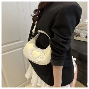 Lace heart crescent bag with adjustable strap shown on shoulder in soft interior setting