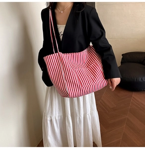Detail of red and white striped canvas tote bag with front pocket and double handles