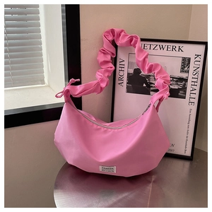 Détail d'un sac hobo rose avec bandoulière à volants et étiquette de logo de mode chic