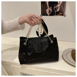 Détail du sac à main noir en cuir gaufré serpent avec poignée en chaîne dorée