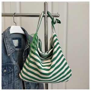 Detail of green and white striped tote bag with soft fabric texture and lace-up side design