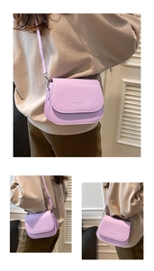 Detail view of a lavender crossbody saddle bag with fashion trend lettering on the flap