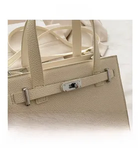 Close-up of off-white lychee leather texture and silver turn-lock hardware on handbag