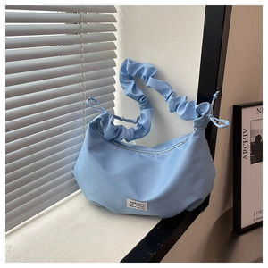 Détail du sac croissant bleu clair avec bandoulière plissée nuage et étiquette mode