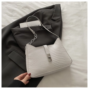 Detail of white crocodile pattern shoulder bag with silver clasp on grey blazer