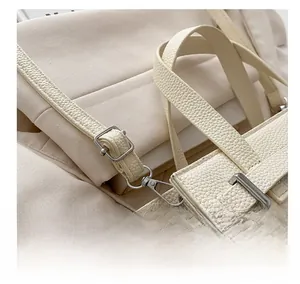 Detail showing adjustable slim shoulder strap with silver buckle on beige leather tote bag