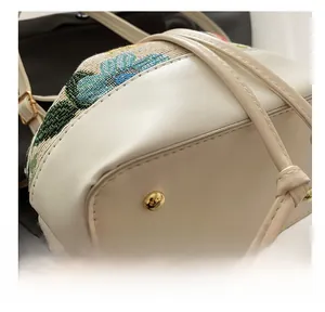 Detail view of white leather bucket bag base with protective gold metal studs